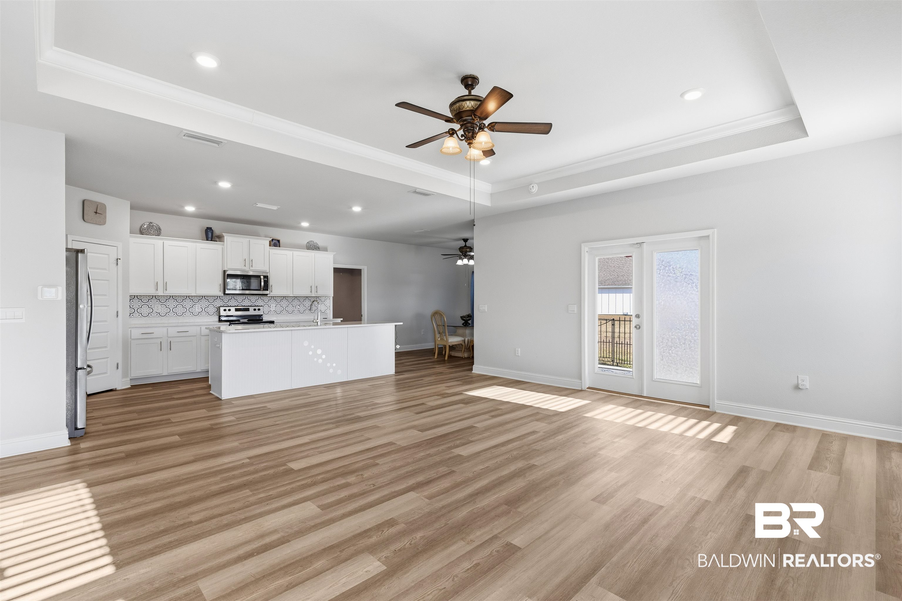 485 Shepard Street Gulf Shores, AL 36542 - Photo 14 of 53 Unfurnished living room with a ceiling fan, a tray ceiling, light wood-type flooring, crown molding, and recessed lighting