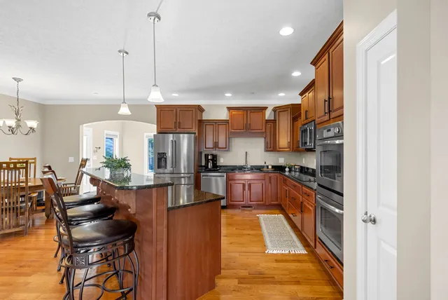 a kitchen with stainless steel appliances granite countertop wooden cabinets a dining table and chairs