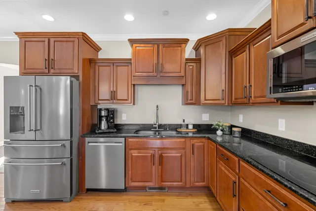 a kitchen with stainless steel appliances granite countertop a sink a stove and a wooden floors