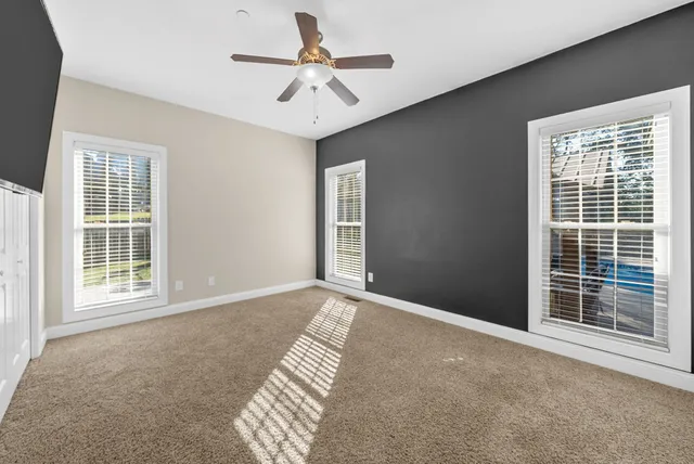 an empty room with a ceiling fan and a window