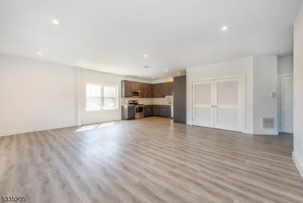 a view of a kitchen and an empty room with wooden floor kitchen view and a window