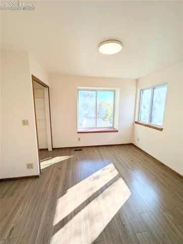an empty room with wooden floor and windows