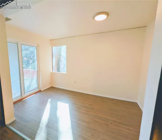 an empty room with wooden floor and windows