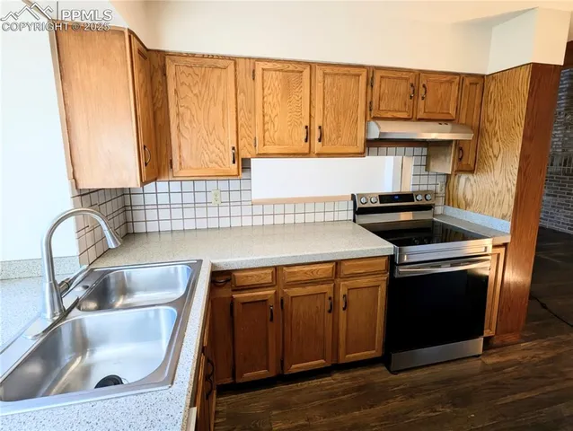a kitchen with granite countertop a sink a stove and wooden cabinets