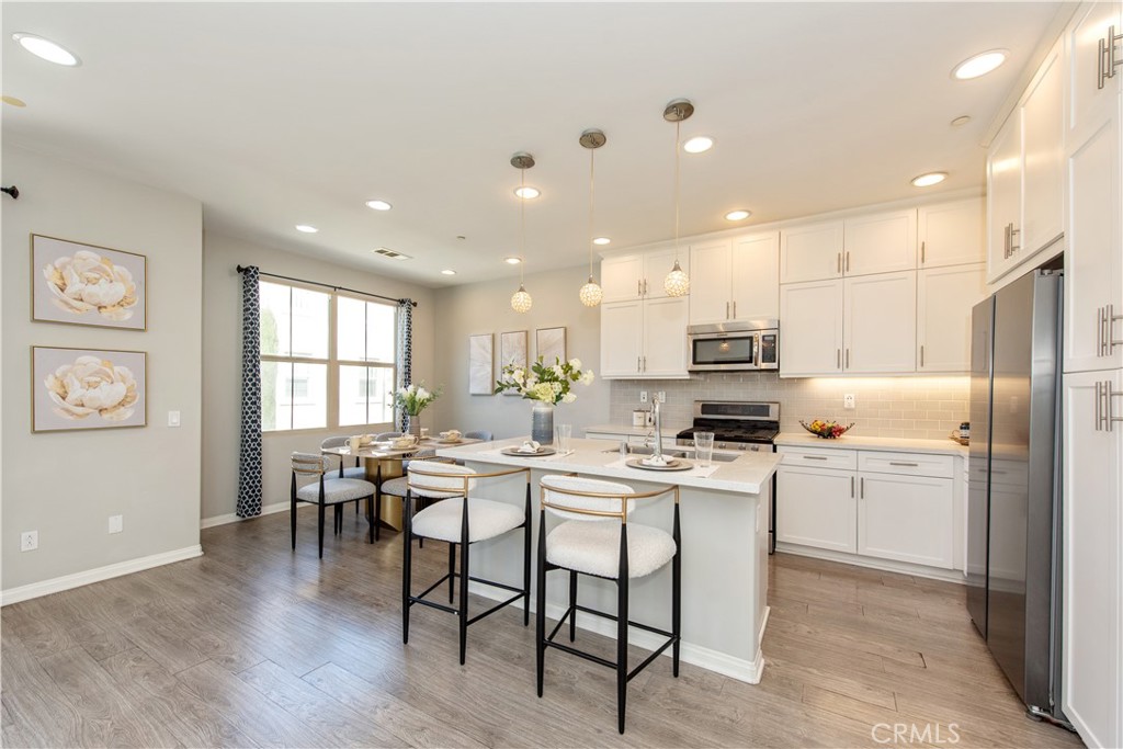 68 Origin Irvine, CA 92618 - Photo 9 of 43 a kitchen with a dining table chairs wooden floor appliances and cabinets