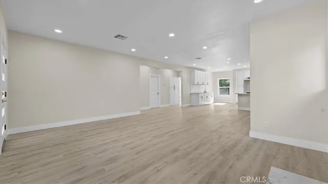 a view of a big room with wooden floor and windows