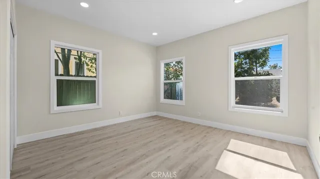 a view of an empty room with a window and wooden floor