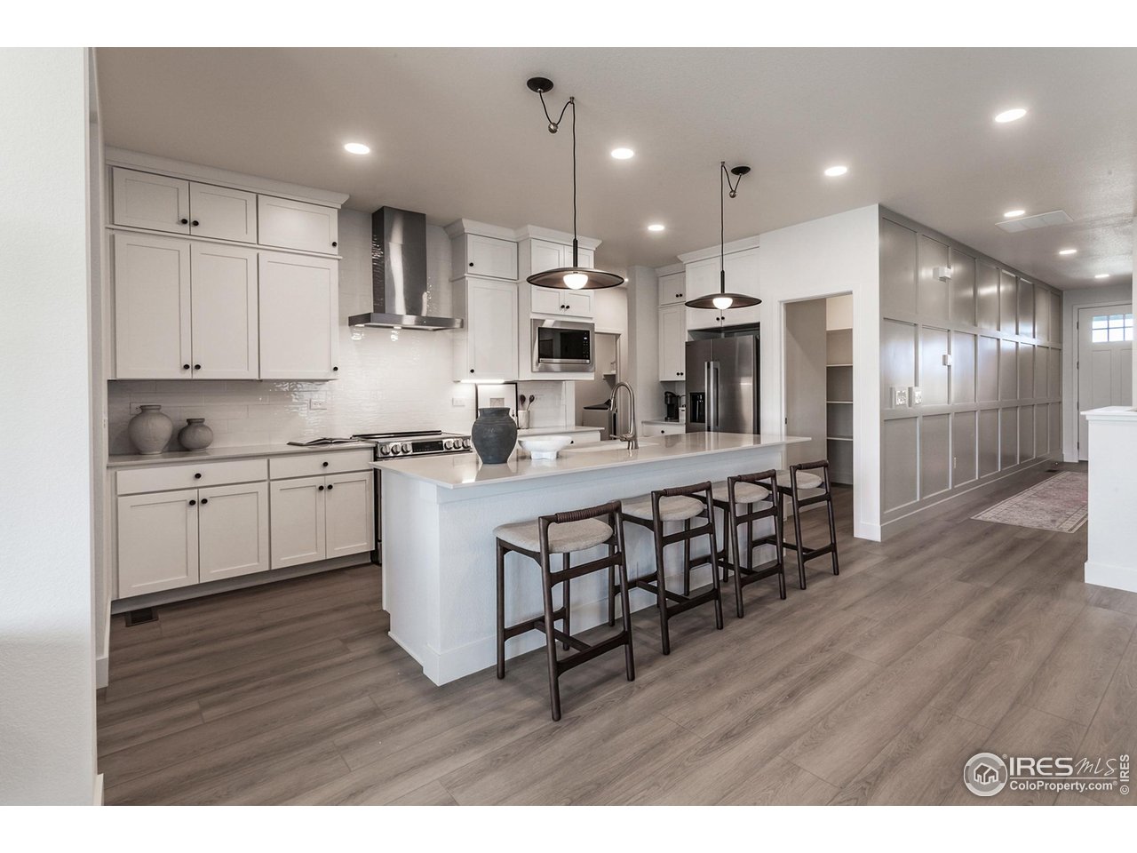 792 Chatter Road Windsor, CO 80550 - Photo 14 of 42 a kitchen with stainless steel appliances kitchen island granite countertop a wooden floors and white cabinets