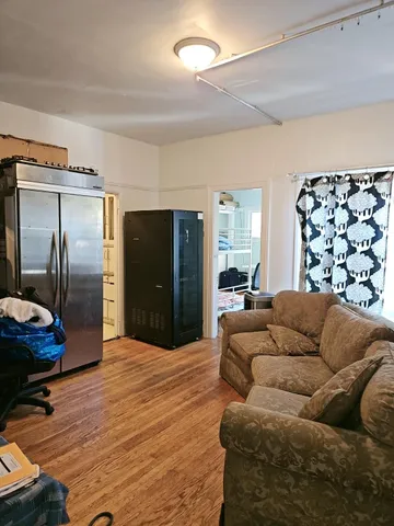 a living room with furniture a flat screen tv and a white refrigerator