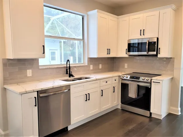 a kitchen with stainless steel appliances granite countertop a sink and a microwave