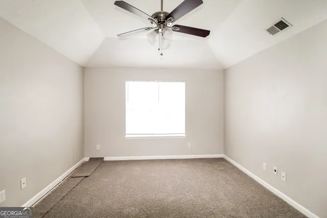 an empty room with a window and a ceiling fan
