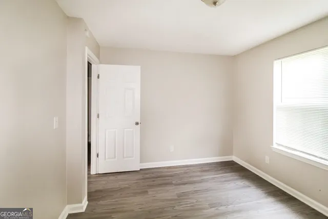 a view of an empty room with wooden floor and a window