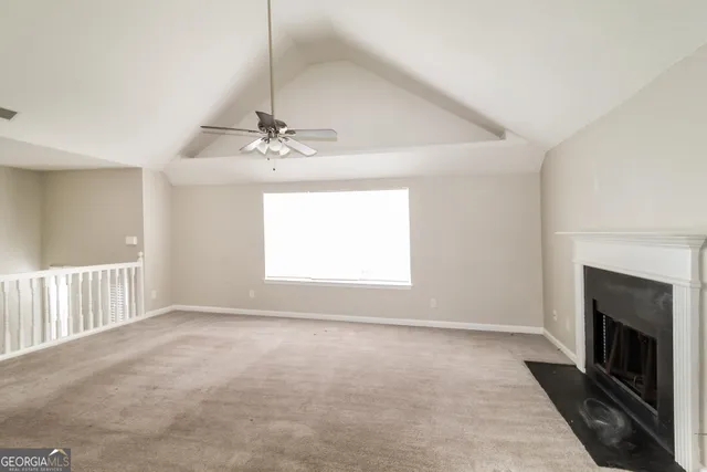 a view of a livingroom with a fireplace a ceiling fan and windows