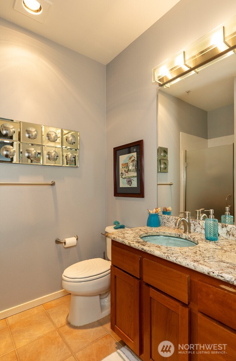 2000 Alaskan Way, Unit 255 Seattle, WA 98121 - Photo 22 of 31 a bathroom with a granite countertop toilet sink and mirror
