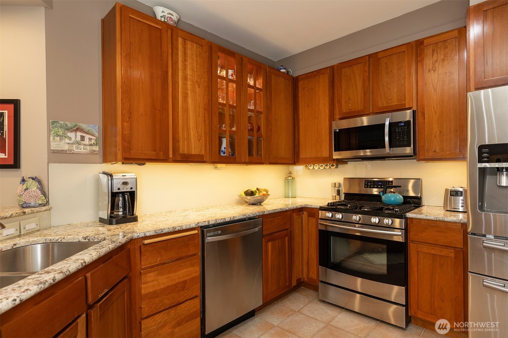 2000 Alaskan Way, Unit 255 Seattle, WA 98121 - Photo 7 of 31 a kitchen with stainless steel appliances granite countertop wooden cabinets a stove top oven a sink and dishwasher
