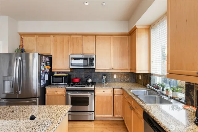 a kitchen with stainless steel appliances granite countertop a sink a stove and a refrigerator