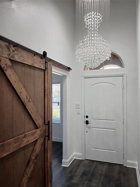 8045 Ballater Drive Fort Worth, TX 76123 - Photo 12 of 26 Foyer entrance featuring dark wood-style flooring, a towering ceiling, and a barn door