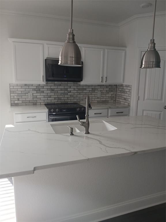 8045 Ballater Drive Fort Worth, TX 76123 - Photo 16 of 26 Kitchen with ornamental molding, a center island with sink, light stone countertops, white cabinets, and black range