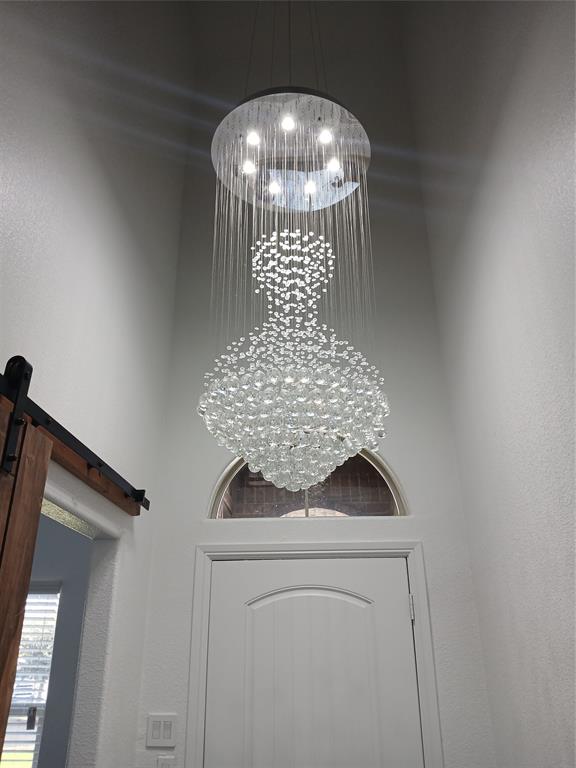 8045 Ballater Drive Fort Worth, TX 76123 - Photo 6 of 26 Detailed view of a chandelier, a barn door, and a textured wall