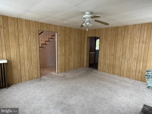 an empty room with chandelier fan and closet area