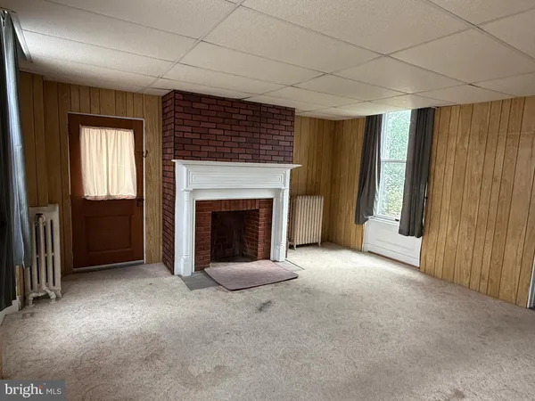 an empty room with windows and fireplace