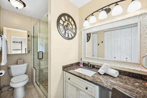 a bathroom with a granite countertop toilet sink and mirror
