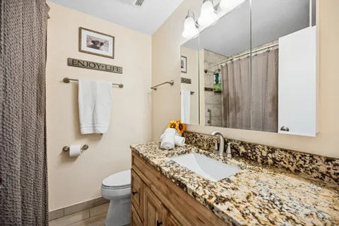a bathroom with a granite countertop sink a mirror and a toilet