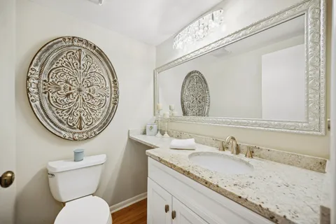 a bathroom with a granite countertop sink a toilet and a mirror