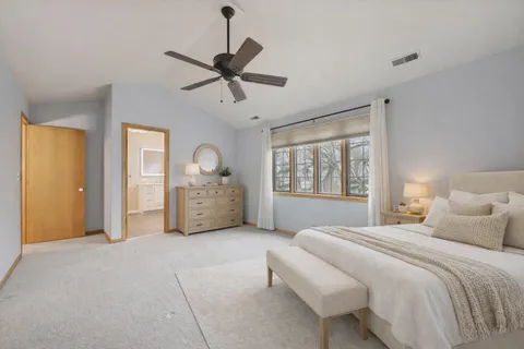 a spacious bedroom with a large bed and a chandelier