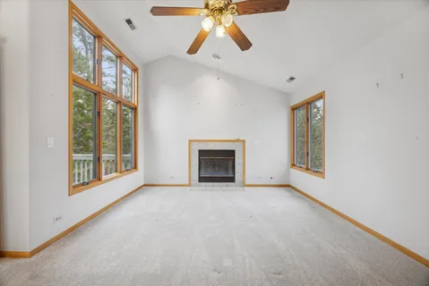 a view of an empty room with chandelier fan and fire place