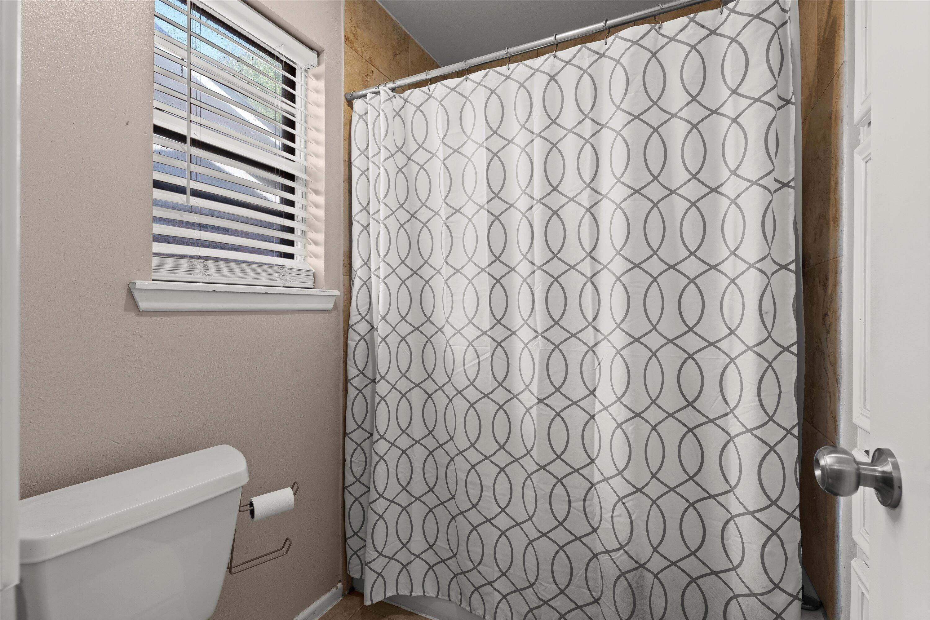 1007 South Howell Street Brownfield, TX 79316 - Photo 9 of 18 a white toilet sitting next to a shower curtain