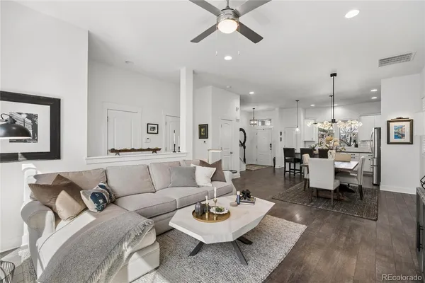 a living room with furniture and a dining table with wooden floor