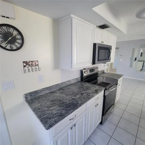 a view of an empty room with window and a kitchen