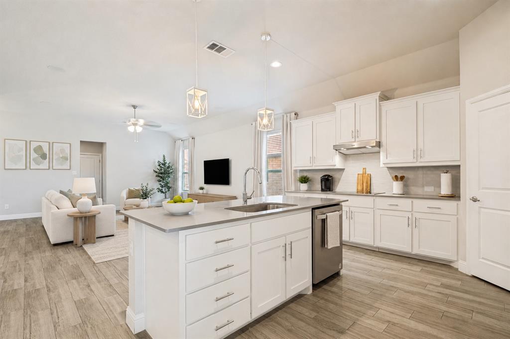 617 Mesquite Grove Road Midlothian, TX 76065 - Photo 9 of 25 Open-concept kitchen featuring an island with an undermount sink, white cabinetry, stainless steel appliances, and wood-finish flooring
