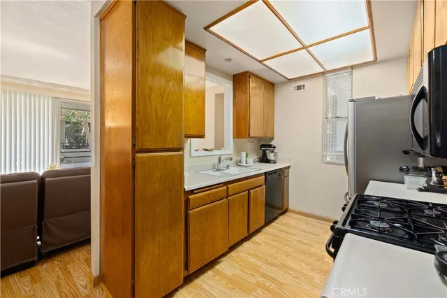 a kitchen with stainless steel appliances granite countertop a refrigerator a sink dishwasher a stove and a dining table with wooden floor