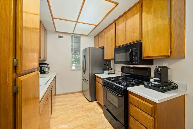 a kitchen with a refrigerator a stove top oven cabinetry a sink and a window