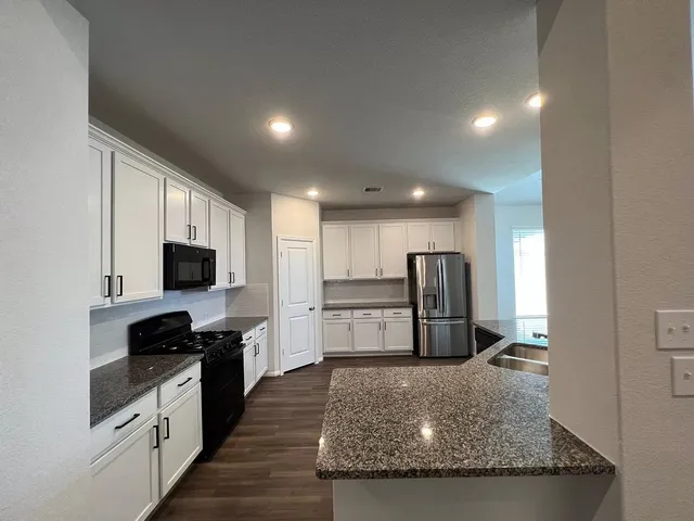 a kitchen with stainless steel appliances granite countertop a refrigerator a stove a sink and a microwave