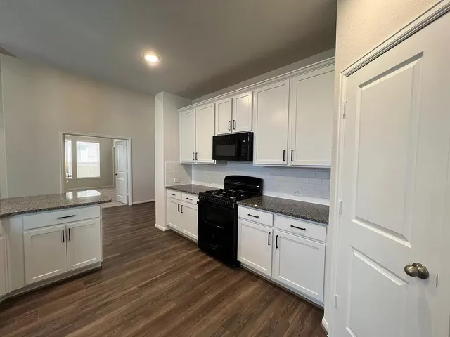 a kitchen with granite countertop a stove top oven sink and cabinets