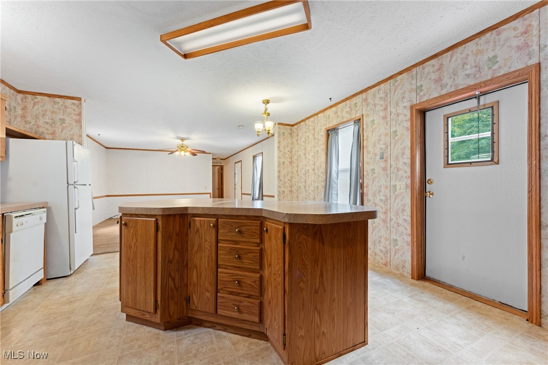6615 Cleveland Road, Unit K2 Ravenna, OH 44266 - Photo 10 of 24 Kitchen featuring brown cabinets, wallpapered walls, ornamental molding, white dishwasher, and a ceiling fan