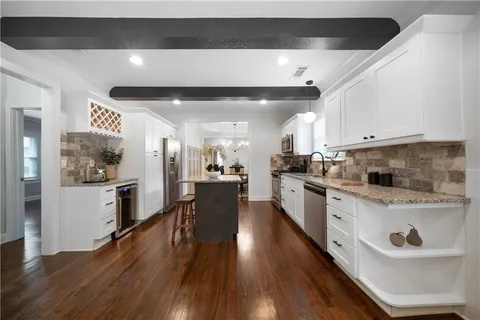 a large white kitchen with lots of counter space a sink and stainless steel appliances