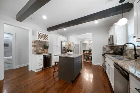 a large kitchen with a center island wooden floor stainless steel appliances and cabinets