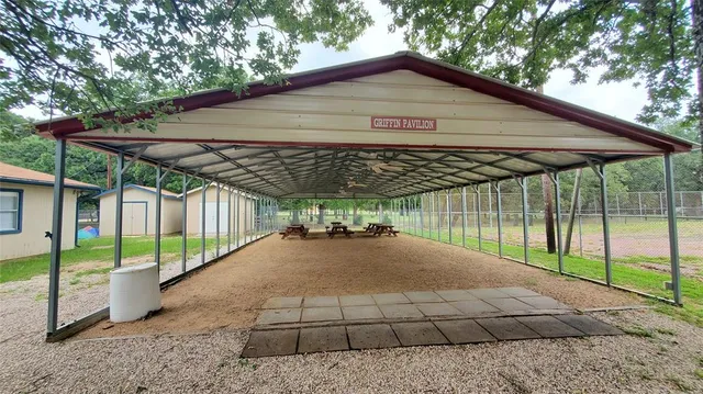 a view of a white house next to a yard with wooden fence