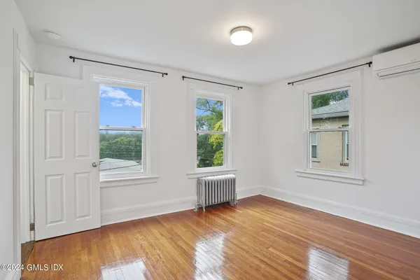a view of an empty room with a window and wooden floor