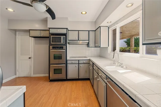 a kitchen with stainless steel appliances a sink cabinets and wooden floor
