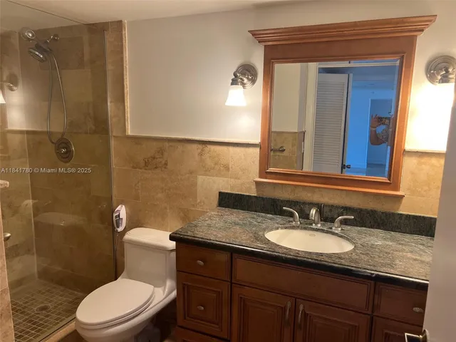 a bathroom with a granite countertop toilet sink and mirror
