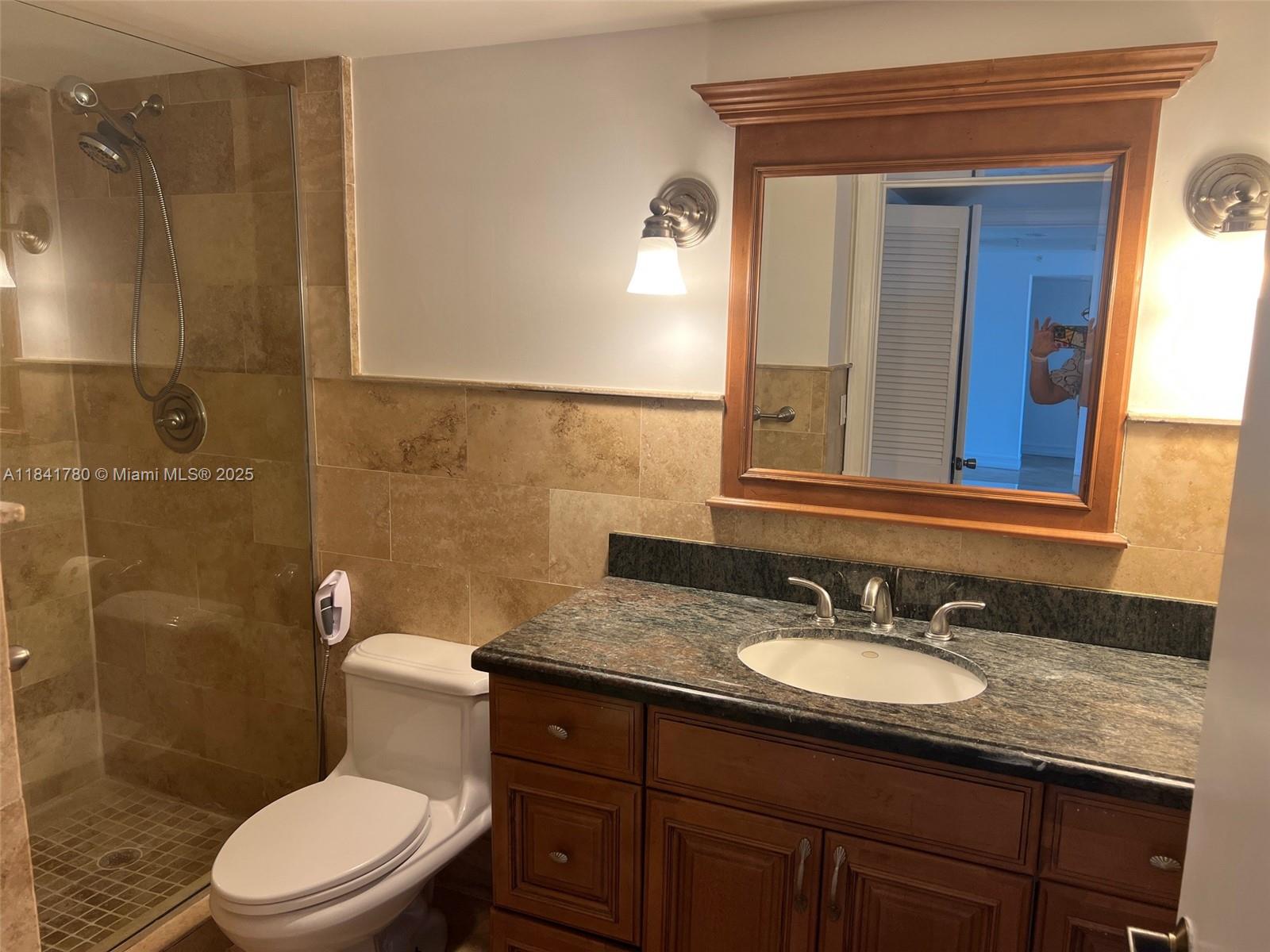 1688 West Avenue, Unit 1005 Miami Beach, FL 33139 - Photo 15 of 34 a bathroom with a granite countertop toilet sink and mirror