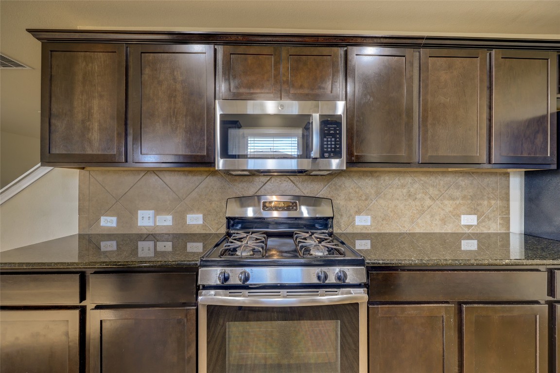 267 Voyager Cove Kyle, TX 78640 - Photo 16 of 40 a kitchen with granite countertop a stove and a microwave