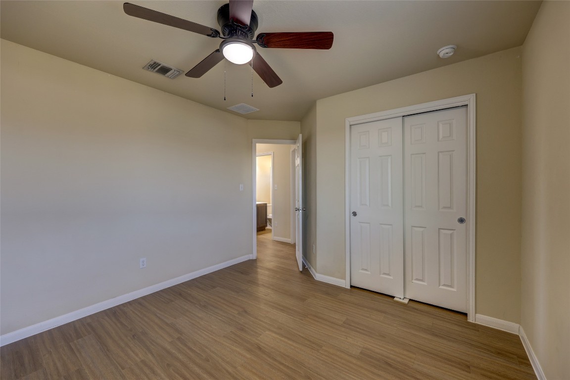 267 Voyager Cove Kyle, TX 78640 - Photo 27 of 40 an empty room with wooden floor chandelier fan and closet area with wooden floor