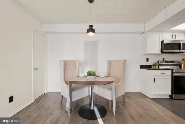 a kitchen with stainless steel appliances granite countertop a dining table chairs a refrigerator and cabinets