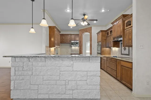 a large kitchen with granite countertop a stove a sink and a refrigerator